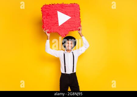 Photo portrait of african american man holding red play button youtube pinata isolated on vivid yellow colored background Stock Photo