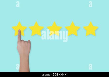 Hand click star rating on blue background. Concept of satisfaction customer service. Stock Photo