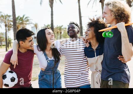 Happy friends from diverse cultures and races laughing and having fun at public park - Multi-ethnic group of young people enjoying on summer holidays Stock Photo