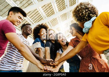 Multiracial happy friends with hands in stack. Multi-ethnic diverse group of college students joining their hands.  Stock Photo