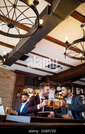 Young businessmen are drinking beer, talking and smiling while resting at the pub Stock Photo