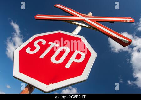 Traffic stop sign at a railway crossing, at background of blue sky. Stock Photo