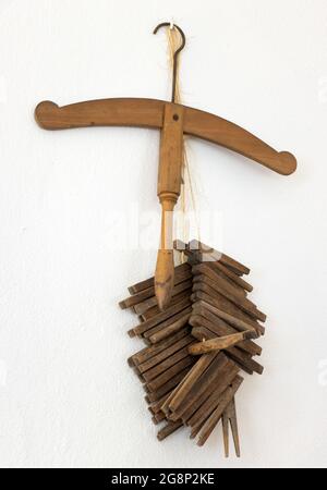 A old wooden coat hanger with pegs hanging on a white wall Stock Photo