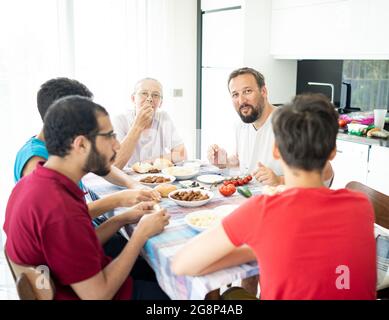 Happy family enjoying eating food in dining room Stock Photo