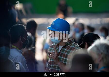 Glasgow, Scotland, UK. 21 July 2021.  PICTURED: An actor dressed as a construction worker wearing a blue hard hat/helmet is seen on set taking direction from on of the producers. Filming on the set of Indiana Jones 5 in the middle of Glasgow city centre as the Hollywood blockbuster sets up Glasgow as New York City. A full production can be seen, with a large cast, producers and extras. The city centre has been changed so that all the shop fronts and building look like 1959 America. Credit: Colin Fisher Stock Photo