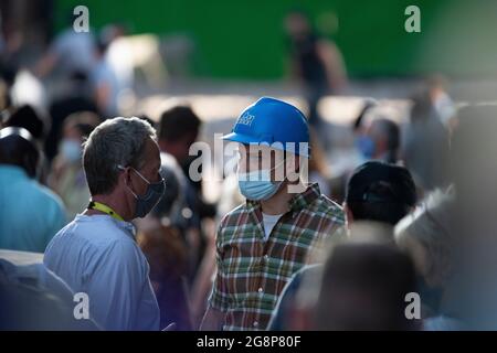 Glasgow, Scotland, UK. 21 July 2021.  PICTURED: An actor dressed as a construction worker wearing a blue hard hat/helmet is seen on set taking direction from on of the producers. Filming on the set of Indiana Jones 5 in the middle of Glasgow city centre as the Hollywood blockbuster sets up Glasgow as New York City. A full production can be seen, with a large cast, producers and extras. The city centre has been changed so that all the shop fronts and building look like 1959 America. Credit: Colin Fisher Stock Photo