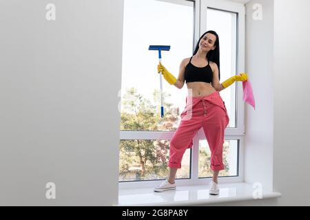 Smiling young woman cleaning windows. Housekeeping theme. Stock Photo