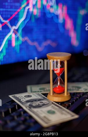 hourglass and dollars on the keyboard on the background of charts Stock Photo