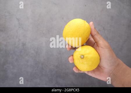 holding Yellow Lemon on black background  Stock Photo