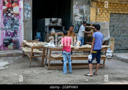 A man selling flat bread to a customer from a bakery on the outskirts of Cairo in Egypt. Stock Photo