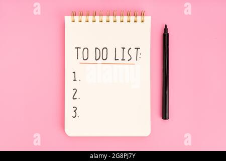 To do list in spiral notepad isolated on pink background. Top view Stock Photo