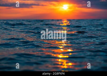Sunset with clouds, warm colors and waves in ocean. Stock Photo