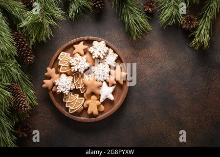 Christmas homemade assorted glazed cookies in wooden plate on brown background. New Year holiday treats. Top view. Xmas greeting card. Copy space. Stock Photo