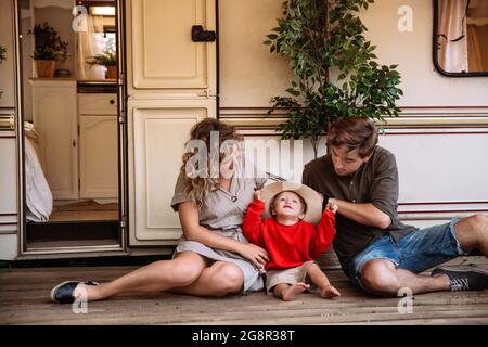 Rv travel with kid: parents with little son sit at trailer van outdoors. Family trip in caravan car Stock Photo