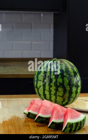 watermelon slices cut in a triangle shape on a wooden board in the kitchen. fresh fruit concept for summer eating Stock Photo