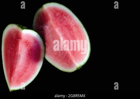 two pieces of fresh, ripe watermelon, one on top of the other, with a black background Stock Photo