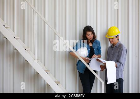 Two Asian engineers, man and woman, discussing in construction site Stock Photo