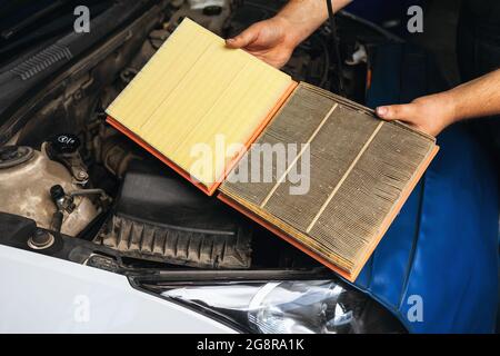 An auto mechanic shows for comparison two engine air filters, one old and the other new Stock Photo