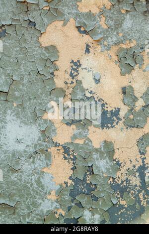 Concrete wall painted with gray-green paint, badly cracked old paint on metal. Vertical photo. Stock Photo