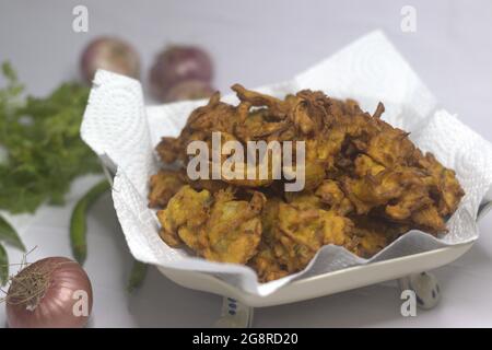 Onion fritters. Deep fried onions slices coated with ground flour and masala. A popular snack in India commonly known as onion pakoda. Shot on white b Stock Photo