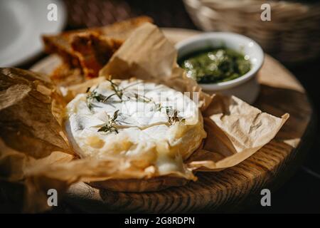 Oven baked camembert cheese with rosemary and pesto sauce Stock Photo