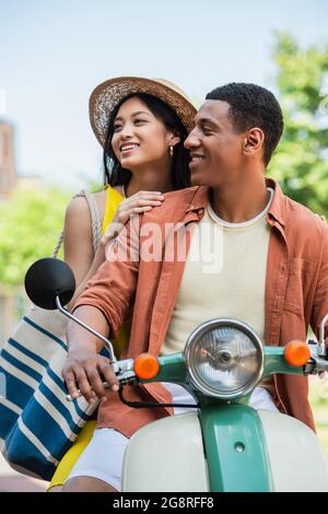 young african american man riding scooter with pretty asian woman Stock Photo