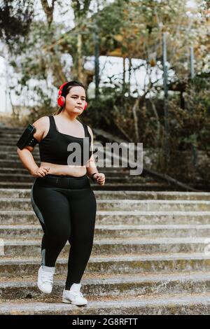 Young beautiful plus size woman in pink sporty top and leggings