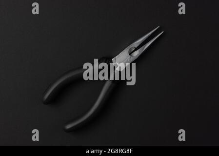 Isolated metal pliers with plastic black handles on a black background Stock Photo