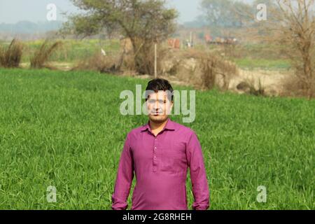 worry less ,indian farmer standing hand folded in his healthy wheat field and smilling Stock Photo