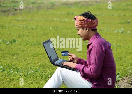 indian farmer using credit card and laptop,farmer using credit card Stock Photo