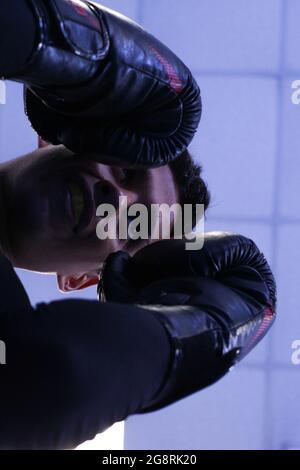 Low angle shot of a Hispanic male boxer wearing boxing gloves and mouth guard training in a gym Stock Photo