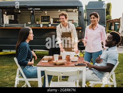 Multi generational people having fun eating at food truck outdoor - Focus on mature woman face Stock Photo