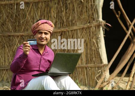indian farmer using credit card and laptop,farmer using credit card Stock Photo