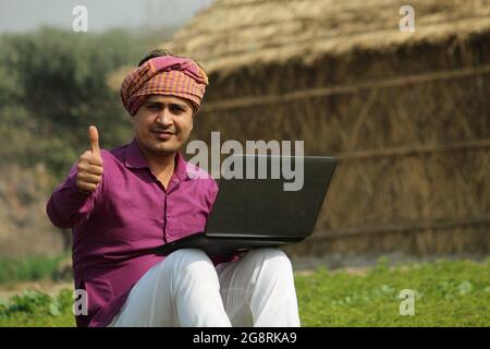 Thumbs Up,indian farmer agriculture field ,using laptop. Stock Photo