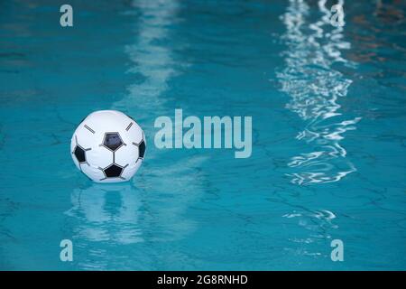 Beach ball in pool. Inflatable ball floating in swimming pool. Stock Photo