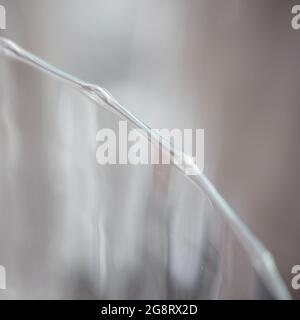 The wavy edge of a glass forms a graphic element in a square. Stock Photo