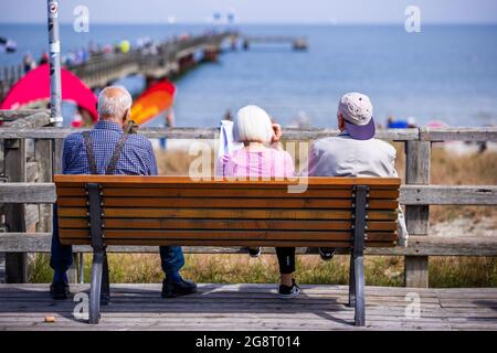 Prerow, Germany. 15th July, 2021. Three elderly holidaymakers are sitting on a bench at the pier. Credit: Jens Büttner/dpa-Zentralbild/ZB/dpa/Alamy Live News Stock Photo