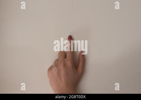 Woman hand with colored fingernails pointing at something or pressing a button. One finger isolated on white background Stock Photo