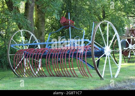 Vintage horse drawn hay rake isolated on grass. Old farming equipment Stock Photo