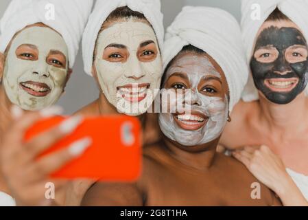 Multiethnic women with face masks taking selfie Stock Photo
