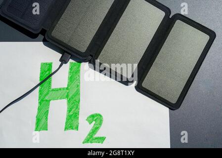 Green hydrogen concept. Solar panel connected to H2 text, symbolizing the generation of hydrogen from solar energy without fossil fuels. Stock Photo
