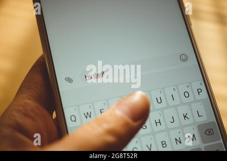 Human hand typing on a white smartphone a message Hi, dad. Stock Photo