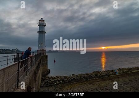 Newhaven Harbour, Edinburgh, Scotland, United Kingdom, 22nd July 2021. UK Weather: hazy sunset by the Firth of Forth with the lighthouse at the end of the harbour wall Stock Photo