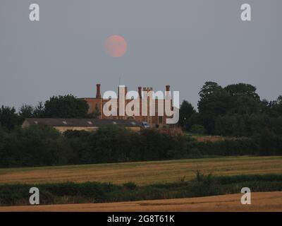 Eastchurch, Kent, UK. 22nd July, 2021. UK Weather: the nearly full moon seen rising above Shurland Hall in Eastchurch, Kent this evening. The full Buck moon will be visible over the next few days. Credit: James Bell/Alamy Live News Stock Photo