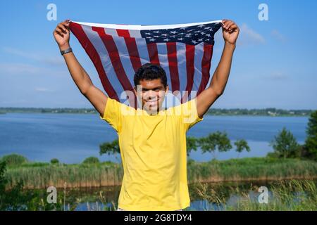 Man looking at camera and proudly holding American flag in his arms Stock Photo