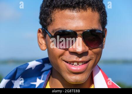 Man looking at camera and proudly holding American flag on his shoulders closeup Stock Photo