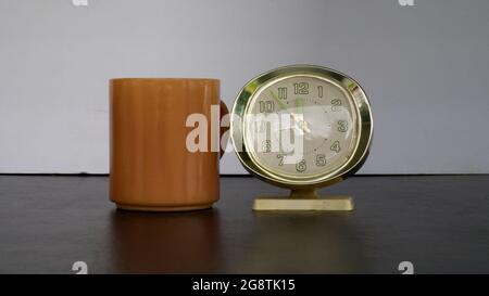 A Brown Coffee Cup and an Old Style Alarm Clock Stock Photo