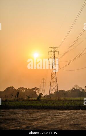 sunset scene of a field with high electric voltage pole and wire Stock ...