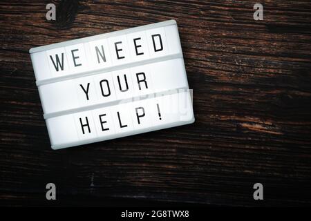 We Need Your Help word text in light box on wooden background Stock Photo