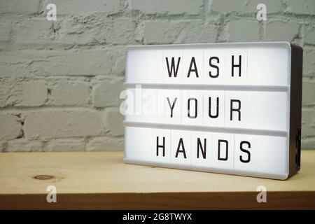 Wash Your Hands word in light box with space coy on white brick and wooden shelves background Stock Photo